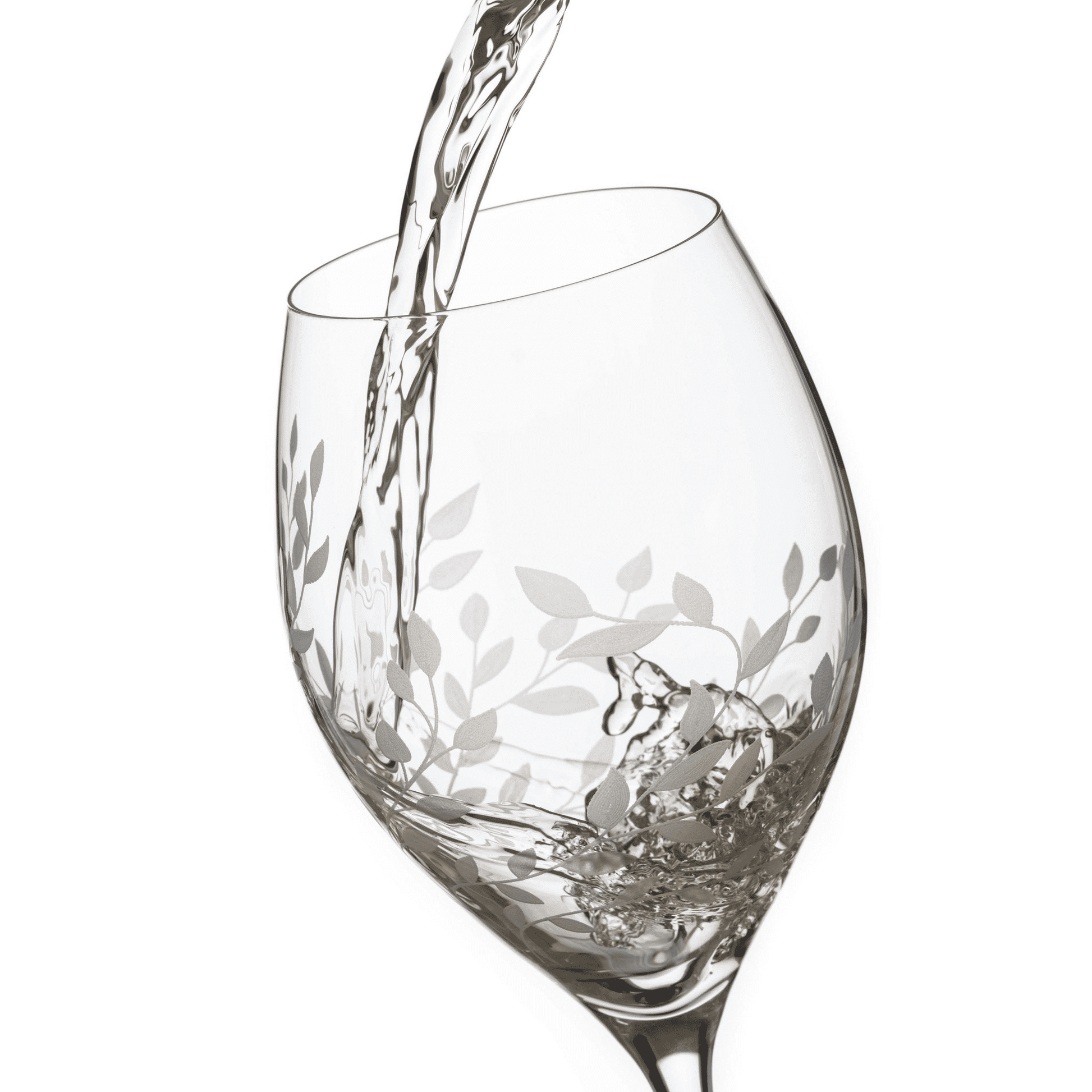 Wine glass with floral etching being filled with white wine on a white background