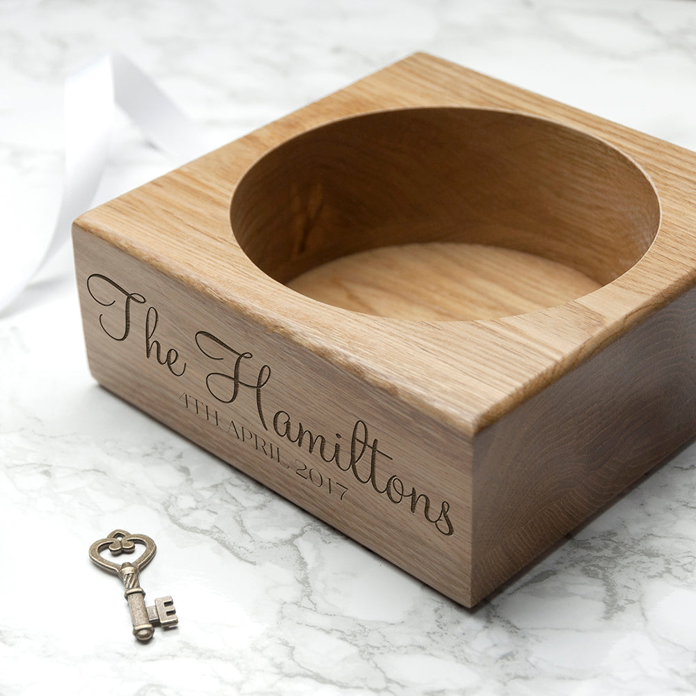 Wooden wine holder engraved with family name and a key on a marble surface