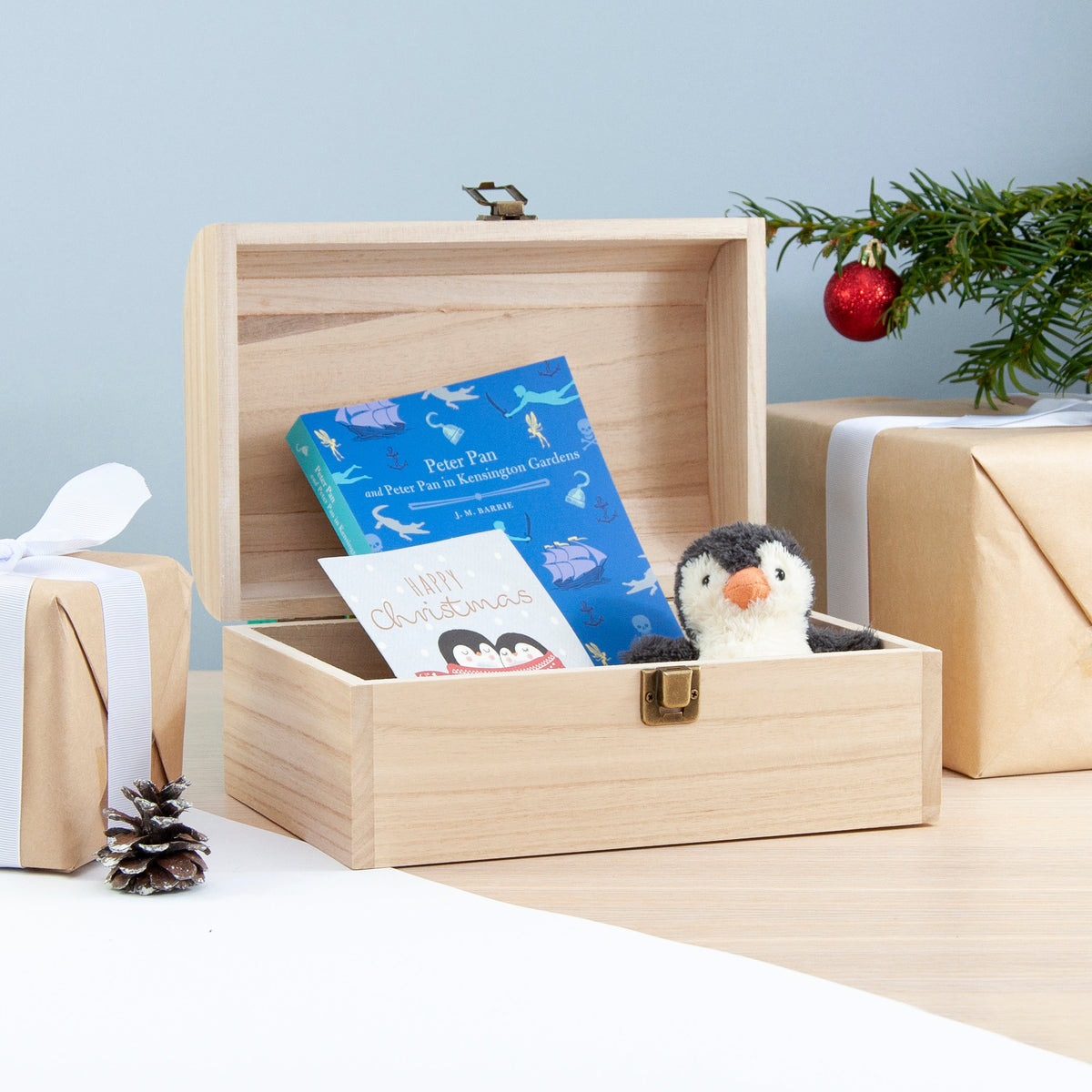 Wooden box with children's books and a penguin toy, Christmas decorations in the background