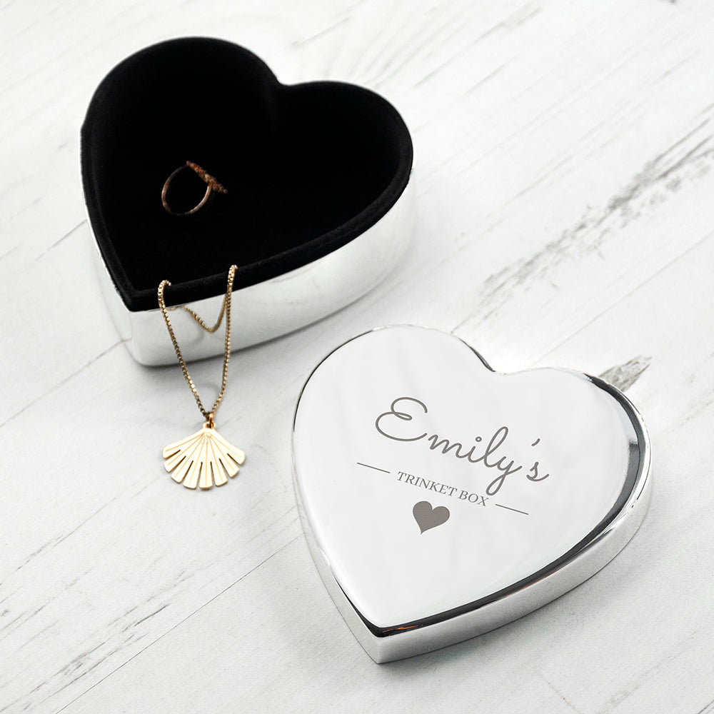 Heart-shaped silver jewelry box with engraved text on a white surface