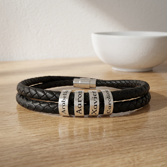 Black braided leather bracelet with name charms on a wooden surface