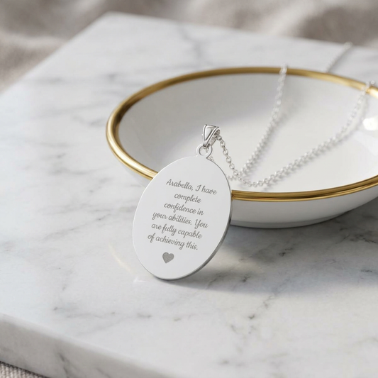 Silver necklace with an engraved pendant on a marble surface