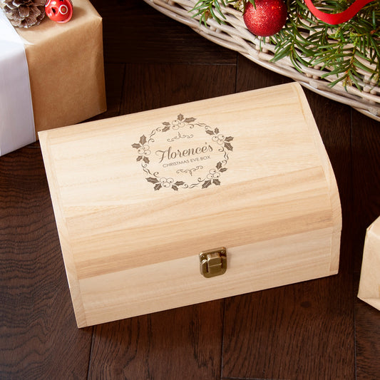Wooden Christmas Eve box with engraved design on a wooden surface with festive decorations.