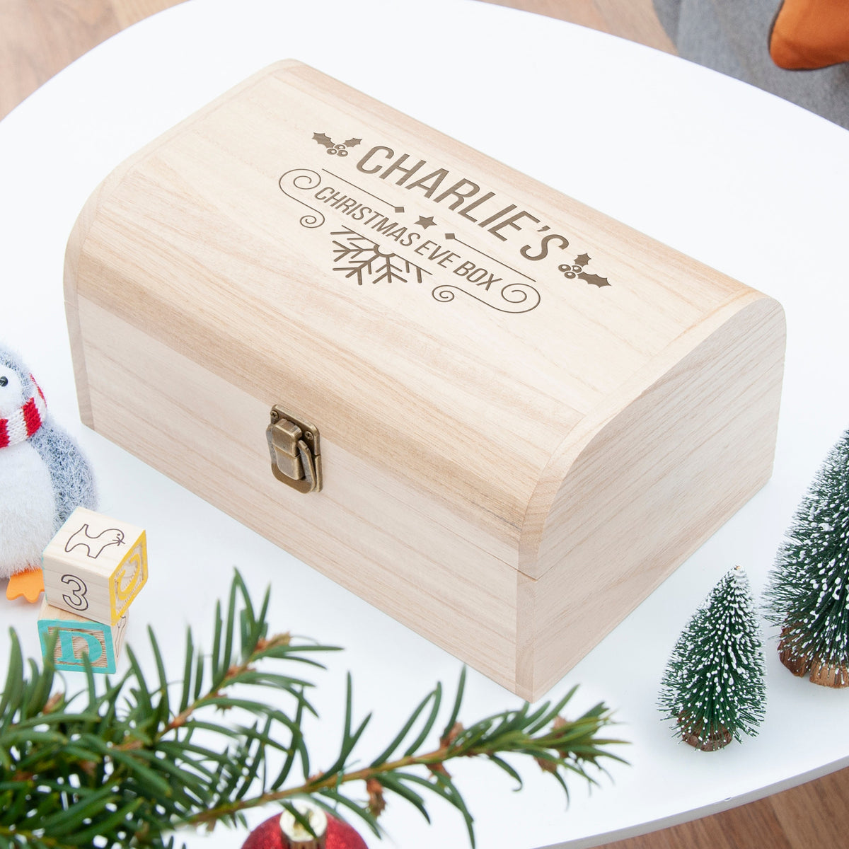 Wooden Christmas Eve box with engraved text on a festive table setting.