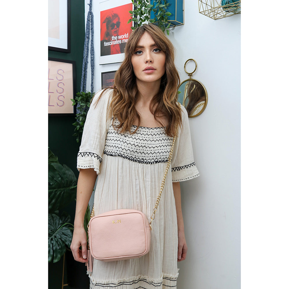 Woman holding a pink crossbody bag with her initials on it