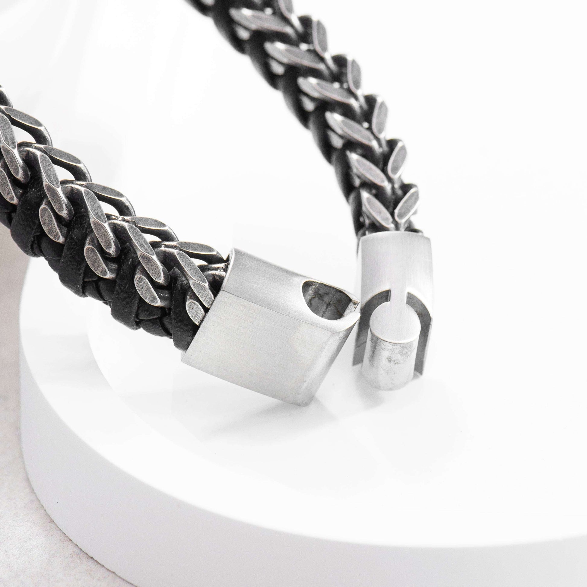 Close-up of a bracelet with braided red cord and silver clasp on a white background
