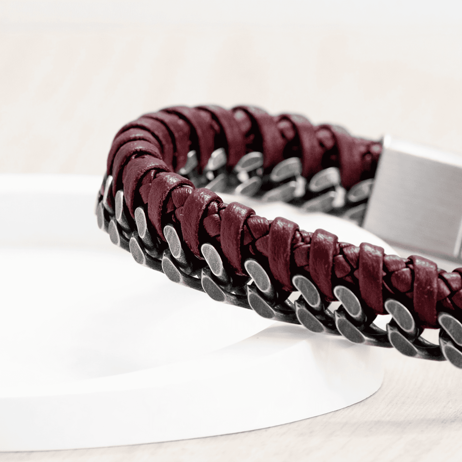 Bracelet with maroon leather and silver chain on a white stand