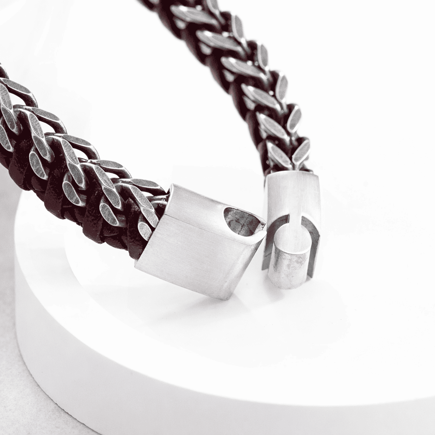 Close-up of a bracelet with braided red cord and silver clasp on a white background