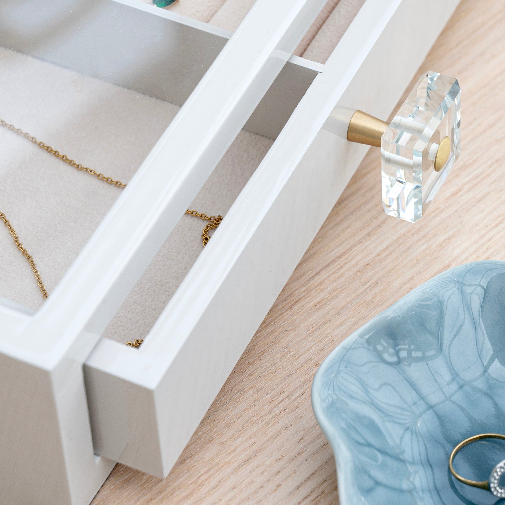 custom-Jewelry box with a gold necklace and a blue decorative bowl on a wooden surface.