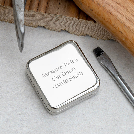 Metallic square object with engraved text on a textured surface