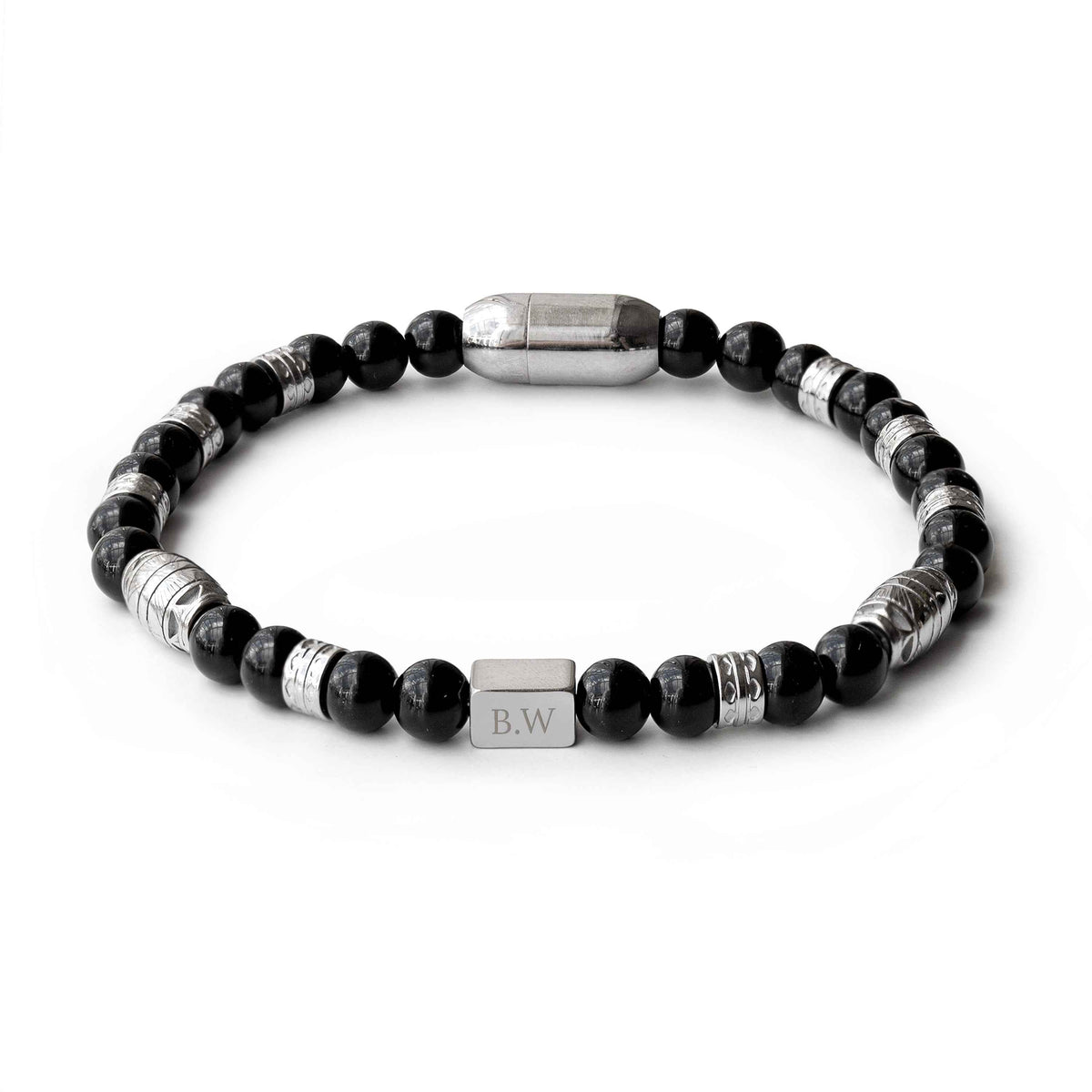 A beaded stretch bracelet featuring black faceted beads, textured silver spacer beads, and a central silver rectangular charm engraved with initials, displayed on a clean white background.