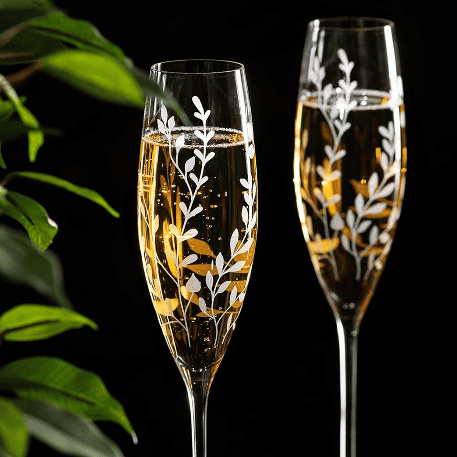 Two champagne flutes with floral etching filled with champagne 