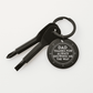 Black keychain with tool bits and engraved message on a white background