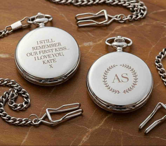 Two pocket watches with engraved messages on a wooden surface
