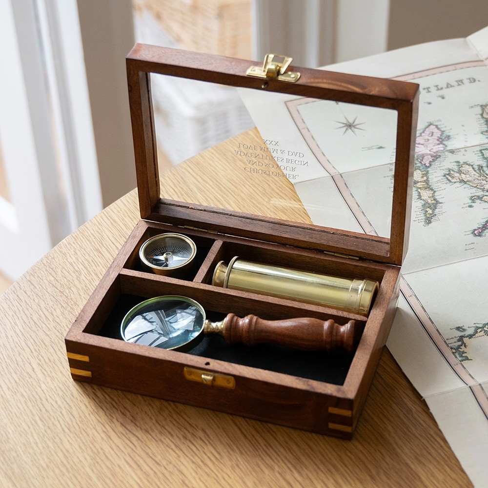 Personalized explorer gift set of together three  instruments—a working pocket compass, miniature extendable telescope, and scholar's magnifying glass—presented in a beautifully crafted wooden keepsake box.The top is engraved wi th a personalized message.