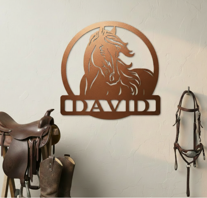 Decorative metal wall art with a horse design and the name 'DAVID' on a light gray wall, with a saddle and bridle in the foreground.