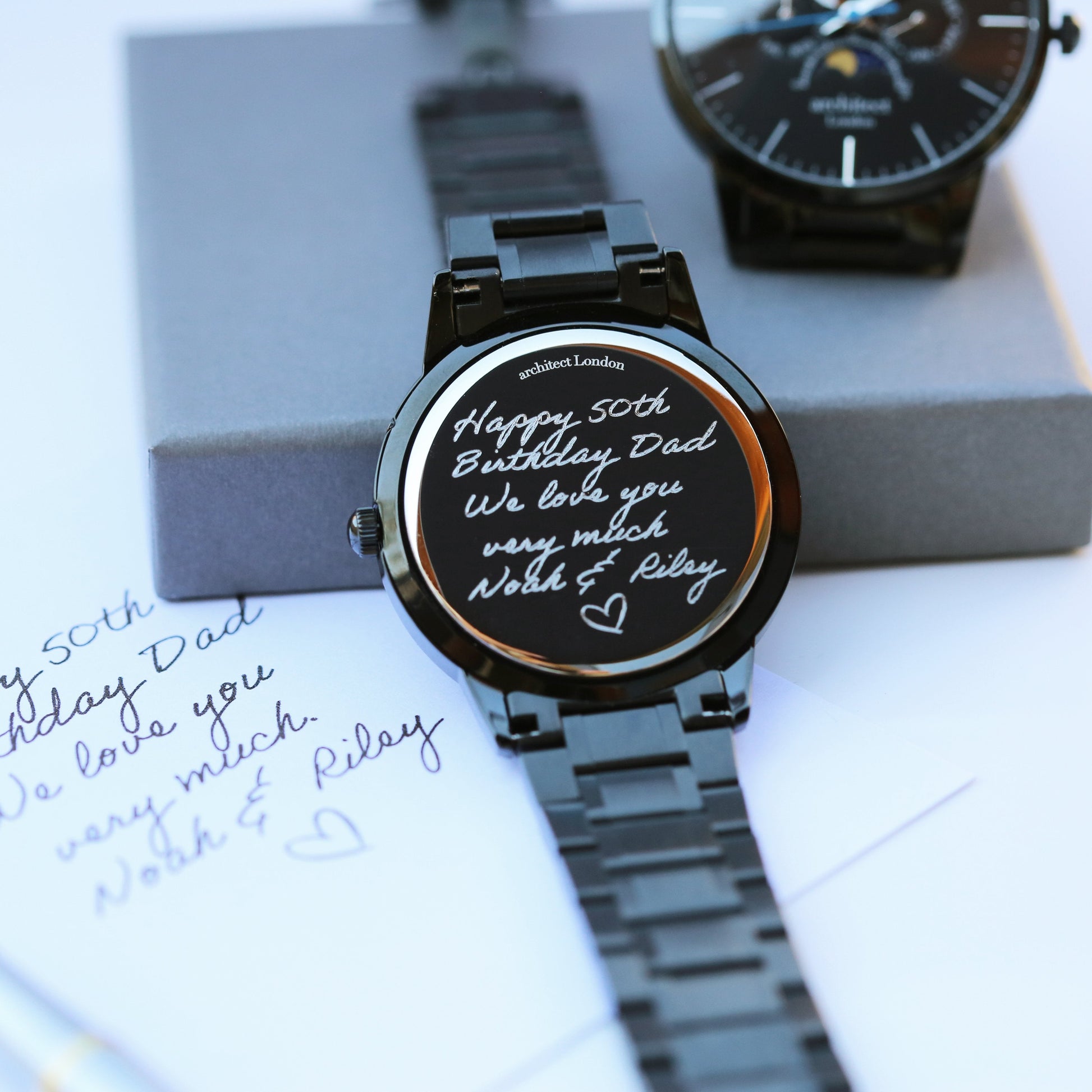Watch with personalized message on the face, placed on a surface with a blurred background