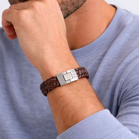 Brown braided bracelet with a silver engraved-clasp on a wrist