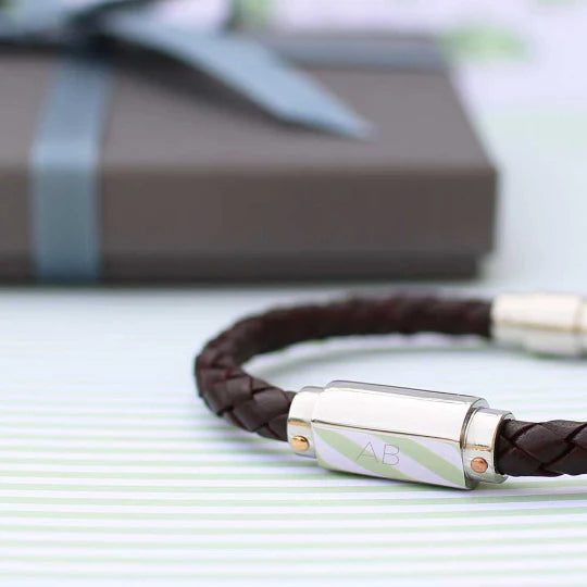 Brown braided leather bracelet with silver clasp on a light surface