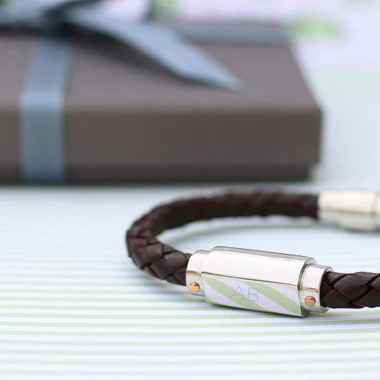 Brown braided leather bracelet with silver clasp on a light surface
