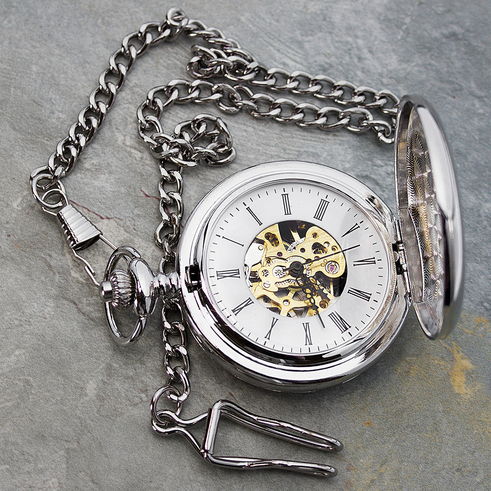 Silver pocket watch with chain on a gray surface