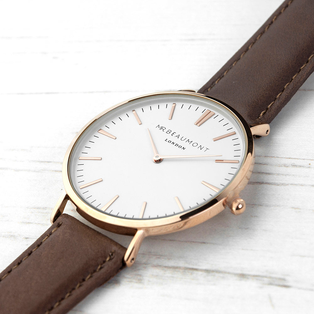 Watch with brown leather strap and rose gold case on a light wooden surface