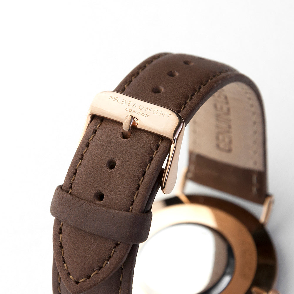 Close-up of a brown leather watch strap with rose gold buckle on a white background