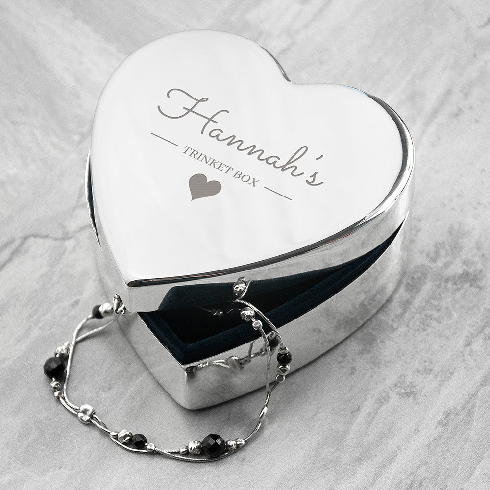 Heart-shaped jewelry box with custom engraving on a marble surface.