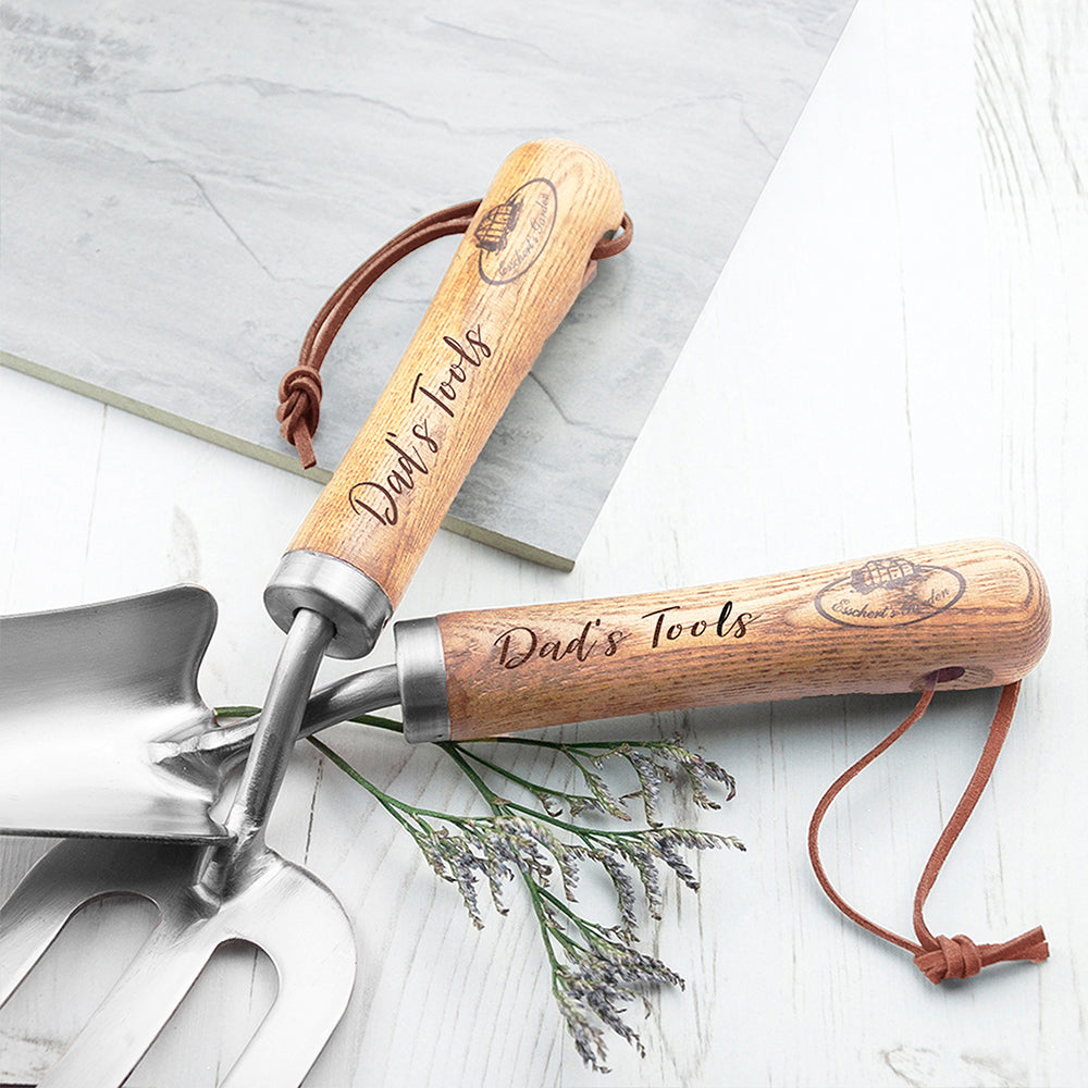 Two wooden-handled gardening tools with 'Dad's Tools' engraving on a light background.