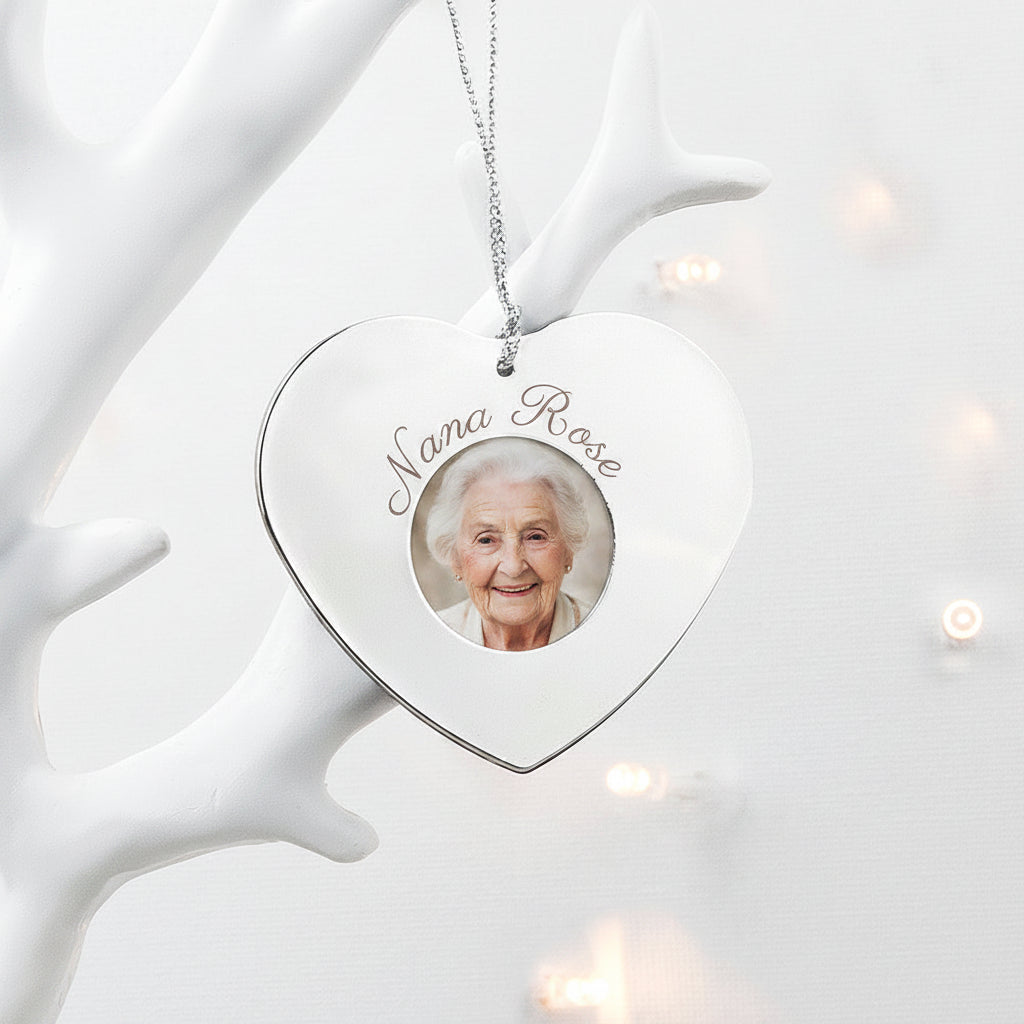 Heart-shaped ornament with a photo frame and engraved name, hanging on a white decorative branch.
