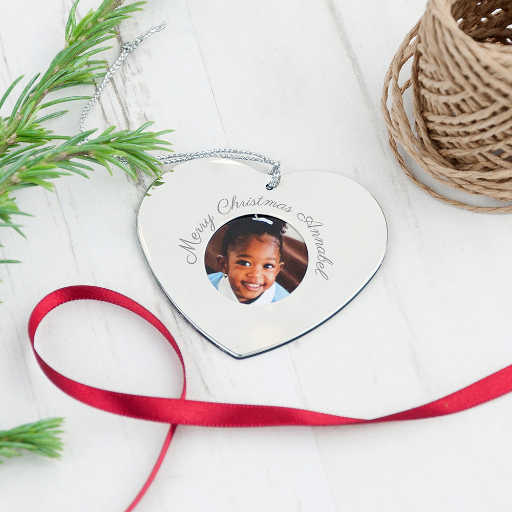Heart-shaped Christmas ornament with a photo of a child and 'Merry Christmas' text, tied with a red ribbon.